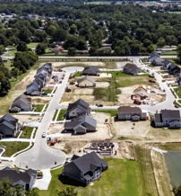 Aerial view of a developing residential area with new homes, construction materials, and a hopeful, sunny atmosphere.