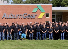 Group of people in matching black t-shirts outside AuburnGear, showing camaraderie and teamwork in a friendly atmosphere.