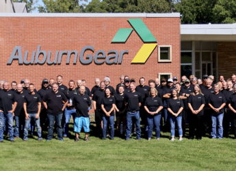 Group of people in matching black t-shirts outside AuburnGear, showing camaraderie and teamwork in a friendly atmosphere.