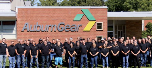 Group of people in matching black t-shirts outside AuburnGear, showing camaraderie and teamwork in a friendly atmosphere.
