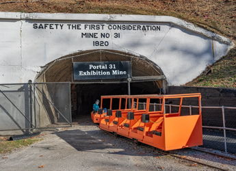 A group stands confidently at a mine entrance, highlighting safety and teamwork, dated 1920.