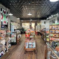 Warm, inviting store with wooden flooring and bright shelves filled with snacks, souvenirs, and local crafts, promoting comfort and curiosity.