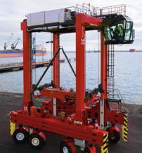 A bright red crane on wheels at a waterfront port, symbolizing efficiency and productivity in a bustling industrial setting.