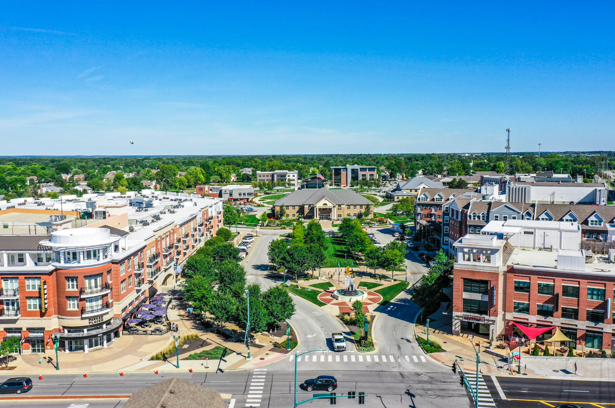 A vibrant urban scene with residential and commercial buildings, green spaces, walkways, and a sunny park, evoking community spirit.