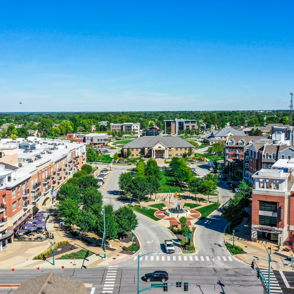 A vibrant urban scene with residential and commercial buildings, green spaces, walkways, and a sunny park, evoking community spirit.