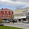 Charming small-town street with historic and modern architecture, greenery, and a relaxed vibe, evoking community and nostalgia.