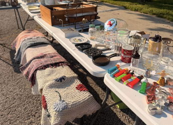 Colorful flea market table with glassware, trinkets, and a wooden box, evoking nostalgia and a sense of discovery.