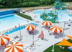 Vibrant water park with a blue pool, colorful slides, umbrellas, and people enjoying fun summer activities.