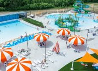 Vibrant water park with a blue pool, colorful slides, umbrellas, and people enjoying fun summer activities.