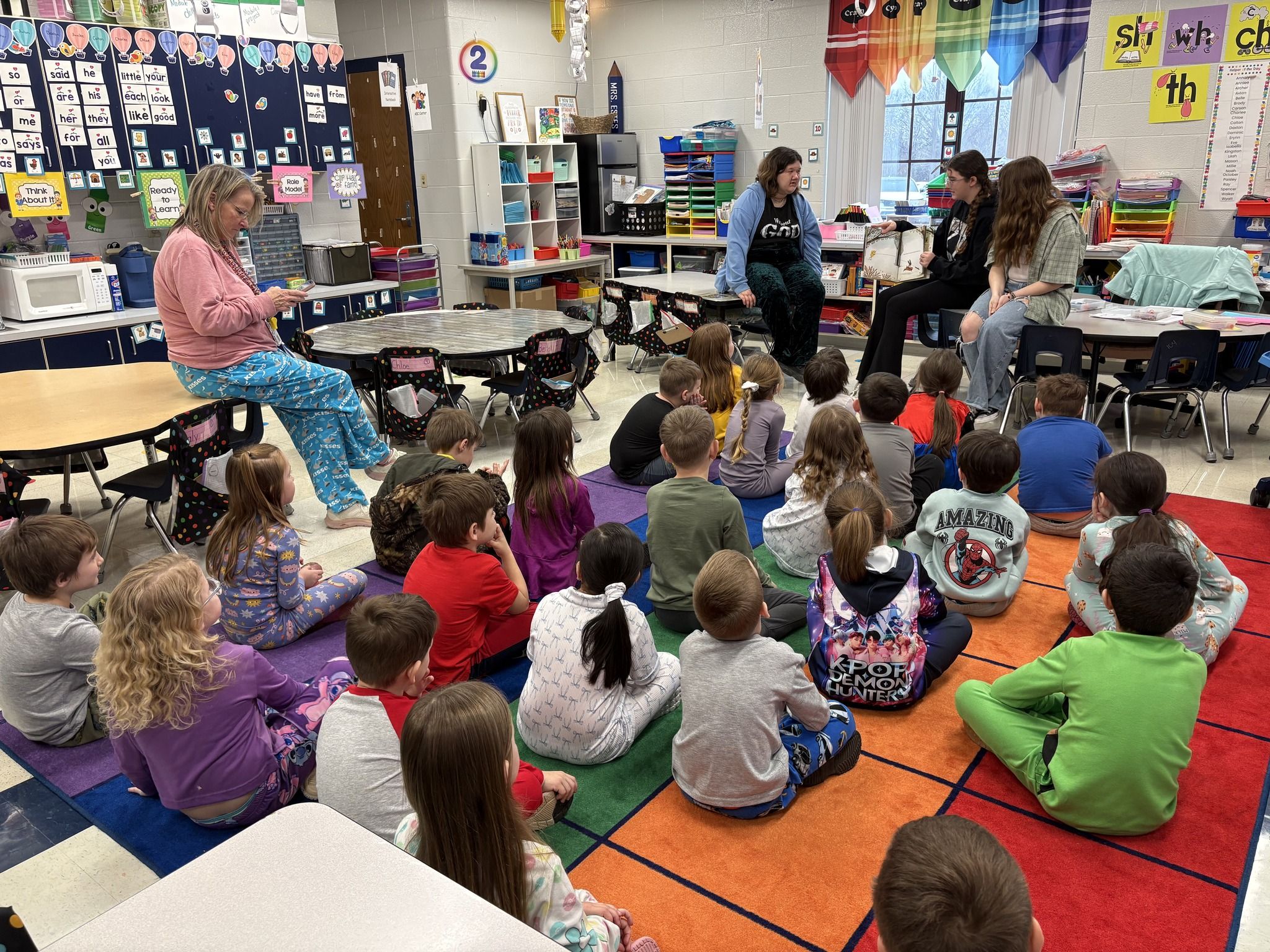 Classroom scene with children in playful attire and adults engaging them, fostering curiosity and a joyful learning environment.