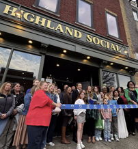 People celebrate a joyful ribbon-cutting ceremony at Highland Social, showcasing community spirit and excitement.