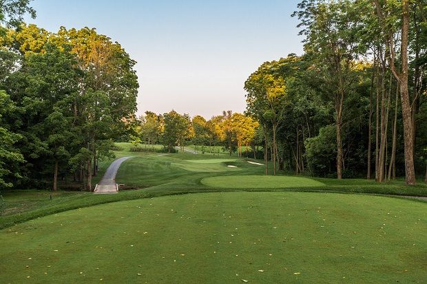 A serene golf course surrounded by greenery, with a winding fairway and soft lighting, evokes peace and connection to nature.