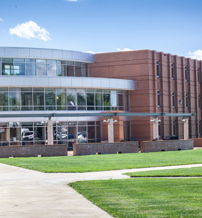 Modern brick and glass building with green lawn, inviting pathways, and bright sky; an uplifting blend of nature and innovation.