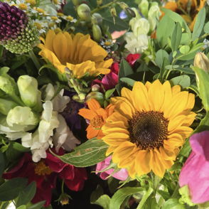 Vibrant flower arrangement: a bright sunflower with pink, white, and purple blooms creates a joyful, uplifting scene.