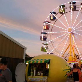 A vibrant carnival scene featuring a colorful Ferris wheel, lively stalls, and joyful crowds evokes happiness and nostalgia.