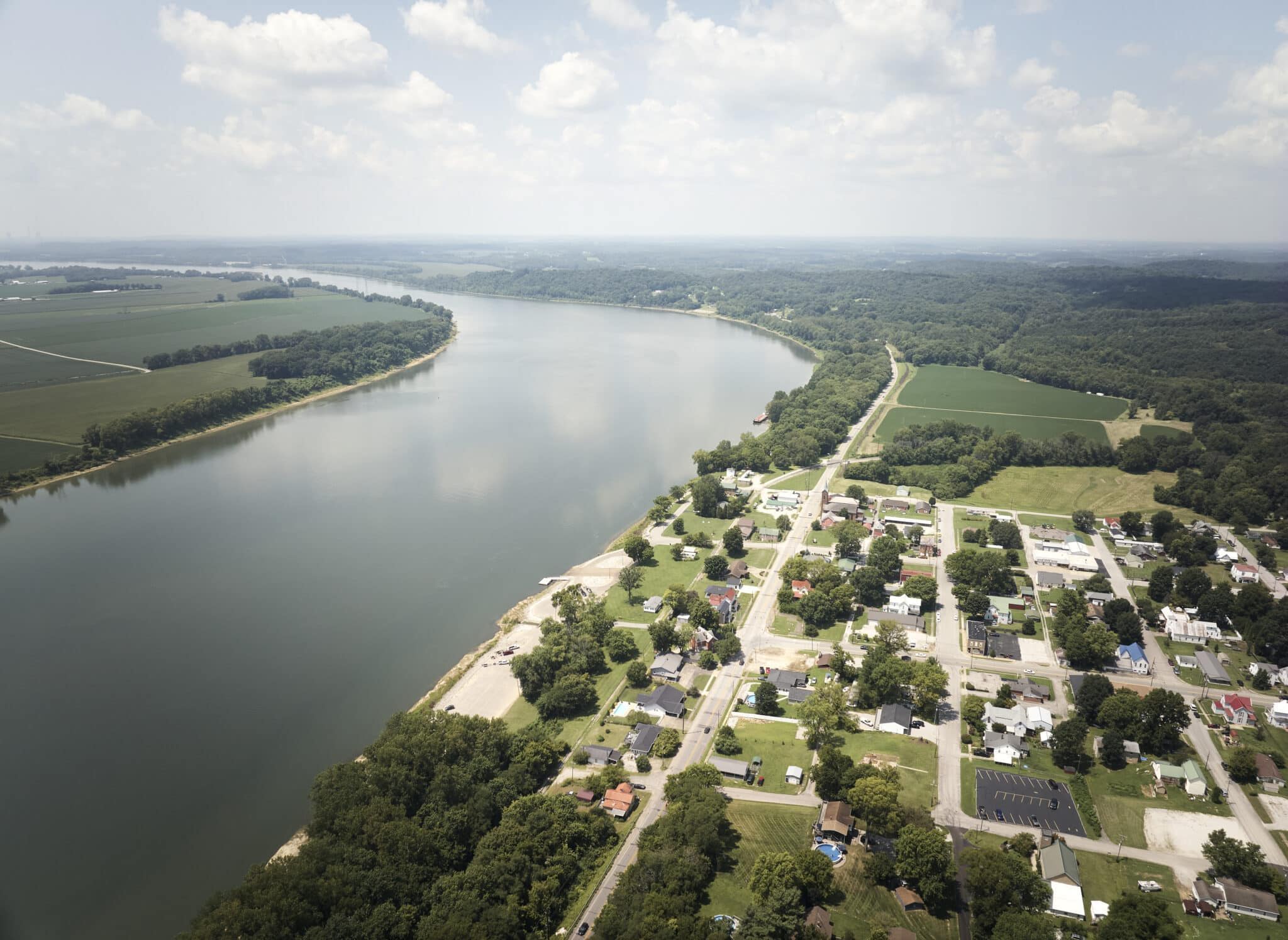 Aerial view of a river winding through a lush landscape, with a small town, evoking tranquility and harmony with nature.