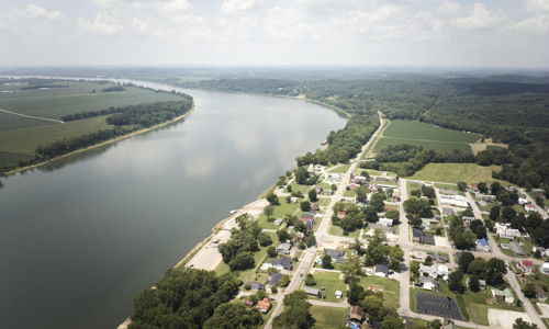 Aerial view of a river winding through a lush landscape, with a small town, evoking tranquility and harmony with nature.