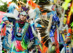 Vibrant individuals in colorful traditional attire with feathers celebrate culture through dance, evoking joy and unity.