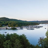 Serene lakeside scene with lush greenery, boats on calm water, evoking peace and relaxation amidst nature's beauty.