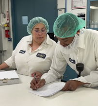 Two professionals in lab coats collaborate in a clean, organized workspace, showcasing teamwork and a commitment to food safety.