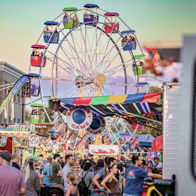 A vibrant carnival scene with a colorful ferris wheel, lively crowds, and a joyful, festive atmosphere.