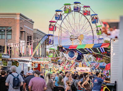 A vibrant carnival scene with a colorful ferris wheel, lively crowds, and a joyful, festive atmosphere.