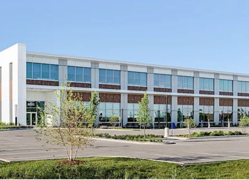 Modern commercial building with large glass windows, lush landscaping, and an inviting atmosphere, conveying professionalism and serenity.