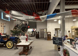 Interior exhibit with a vintage airplane and classic car; vibrant colors evoke nostalgia and celebrate history and innovation.