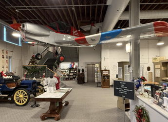 Interior exhibit with a vintage airplane and classic car; vibrant colors evoke nostalgia and celebrate history and innovation.