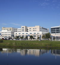 Modern urban scene with white glass buildings, calm water reflection, greenery, and a bright sky conveying harmony and optimism.
