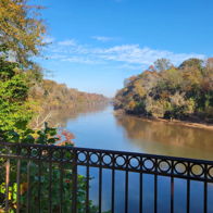 Serene river view surrounded by colorful autumn trees and a blue sky, inviting a sense of tranquility and connection to nature.