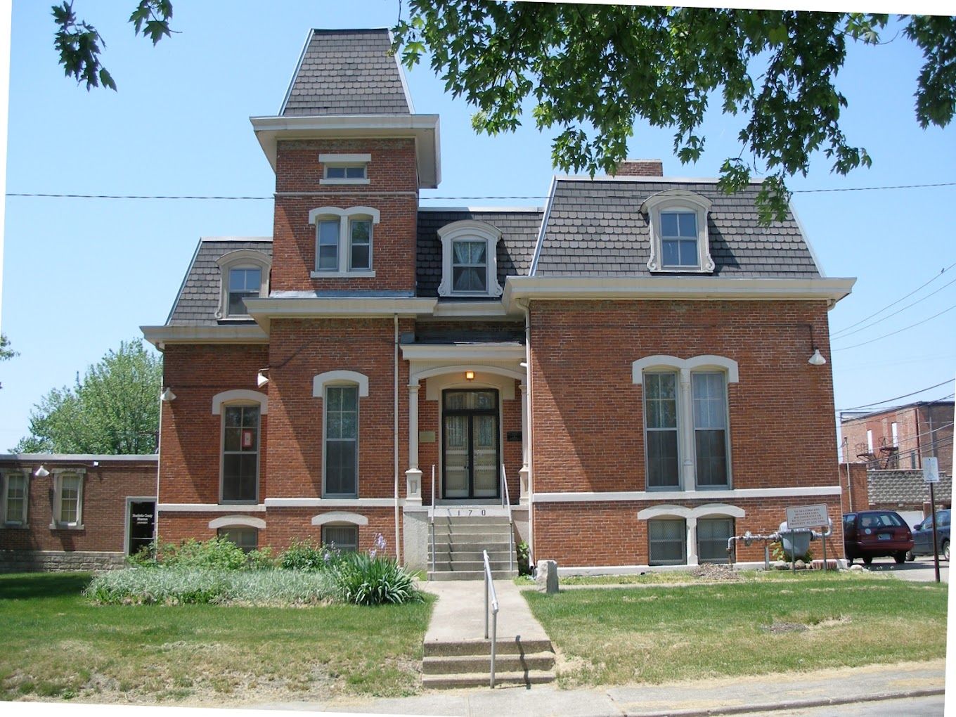 Victorian brick building with a tower, large windows, welcoming entrance, and serene atmosphere evokes nostalgia and charm.