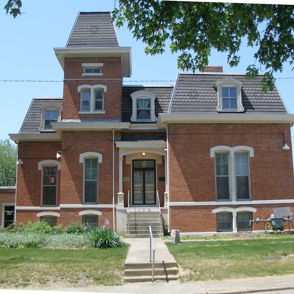 Victorian brick building with a tower, large windows, welcoming entrance, and serene atmosphere evokes nostalgia and charm.