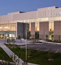 A modern office building with large windows reflects innovation and warmth, set in a welcoming twilight atmosphere.