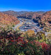 Autumn landscape with vibrant foliage, winding road, and a serene settlement under a clear blue sky invites tranquility and reflection.