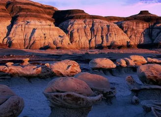 Dramatic landscape with sculptural rocks and layered hills, bathed in warm golden hour light, evoking serenity and awe.