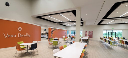 Bright, modern café interior with orange wall, white tables, colorful chairs, and ample natural light, fostering a lively atmosphere.