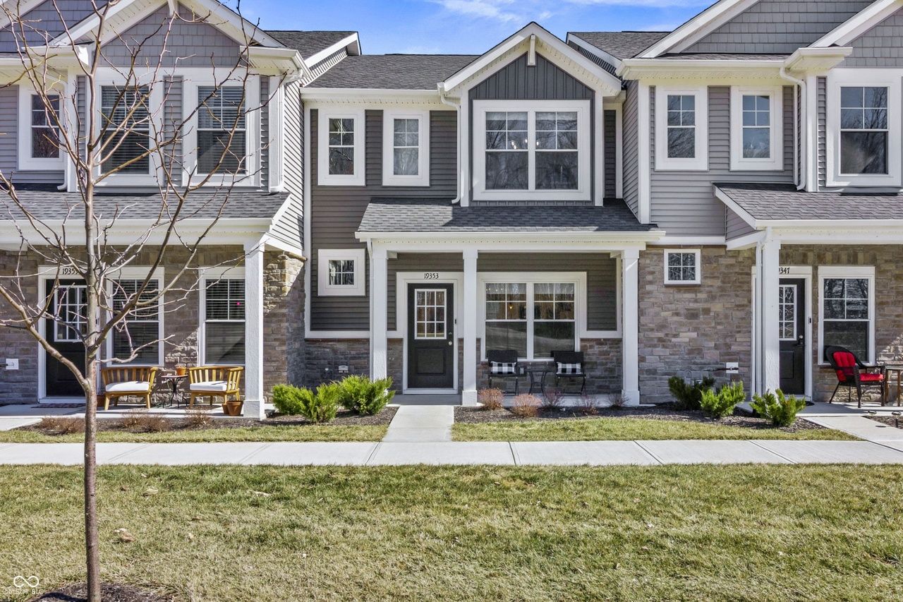 Contemporary townhouses with stone and siding, inviting porches, vibrant red chair, and a welcoming neighborhood feel.
