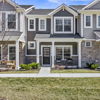 Contemporary townhouses with stone and siding, inviting porches, vibrant red chair, and a welcoming neighborhood feel.