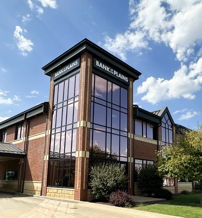 Modern brick building with glass windows, bright sky, and landscaping, evoking calmness, professionalism, and optimism.