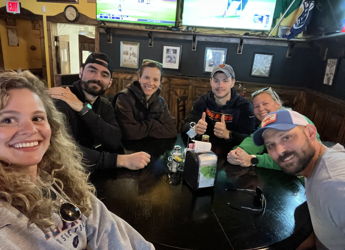 A cheerful group of people at a casual gathering, smiles and relaxed vibes in a warm, inviting pub setting.