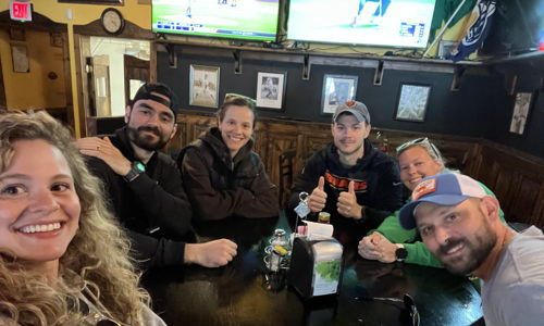 A cheerful group of people at a casual gathering, smiles and relaxed vibes in a warm, inviting pub setting.