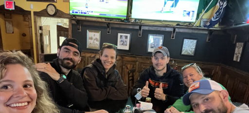 A cheerful group of people at a casual gathering, smiles and relaxed vibes in a warm, inviting pub setting.