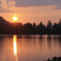 Serene sunset over a tranquil lake with warm hues reflecting on water, evoking calmness and appreciation of nature.