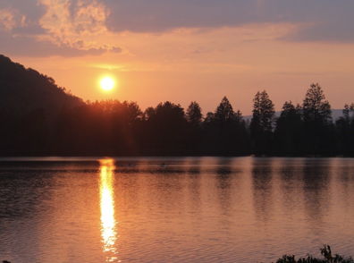 Serene sunset over a tranquil lake with warm hues reflecting on water, evoking calmness and appreciation of nature.