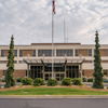 Modern building with flat roof, large windows, manicured trees, and elegant landscaping, evoking stability and professionalism.