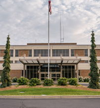Modern building with flat roof, large windows, manicured trees, and elegant landscaping, evoking stability and professionalism.