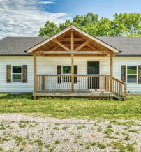 Cozy single-story home with a white exterior, wooden porch, surrounded by trees, evoking comfort and tranquility.