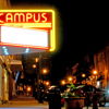Vibrant nighttime street scene with a retro neon "CAMPUS" sign, evoking nostalgia, warmth, and a lively community atmosphere.