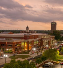 Twilight view of a vibrant urban campus, with warm lights and a calm, reflective atmosphere transitioning into night.